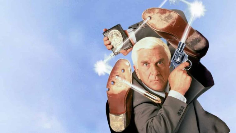 The Naked Gun Movie Wallpaper with Leslie nielsen in a grey suit holding a shooting gun and a police badge