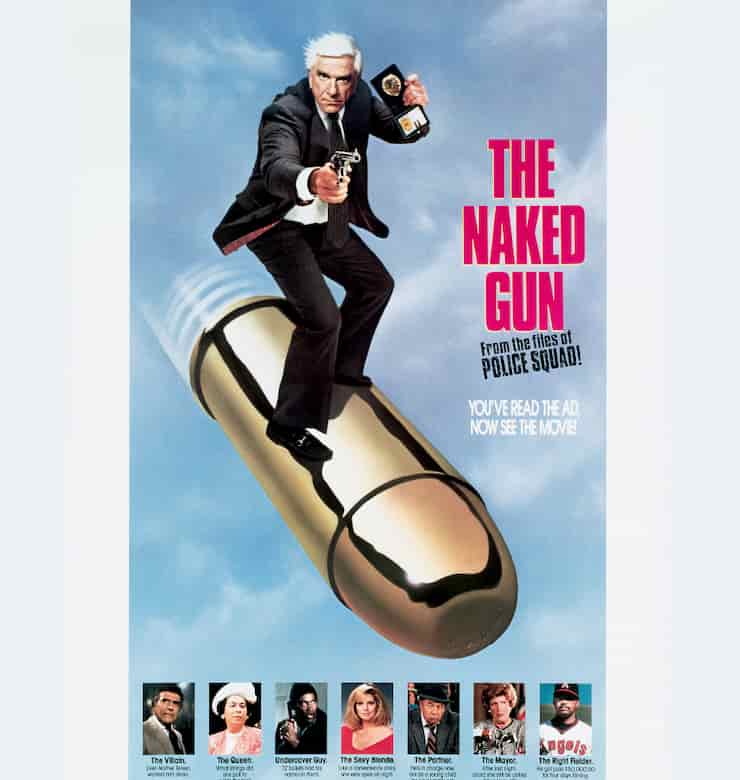 Frank Drebin in a dark suit holding a gun and police badge while riding a big bullet in a blue sky