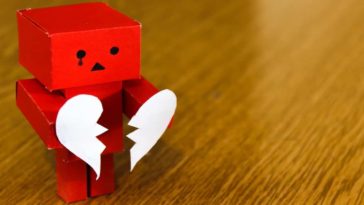 Red square paper robot holding paper broken heart