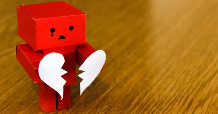 Red square paper robot holding paper broken heart