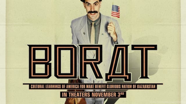 Borat Movie wallpaper Borat in a grey suit and pale background holding a small american flag