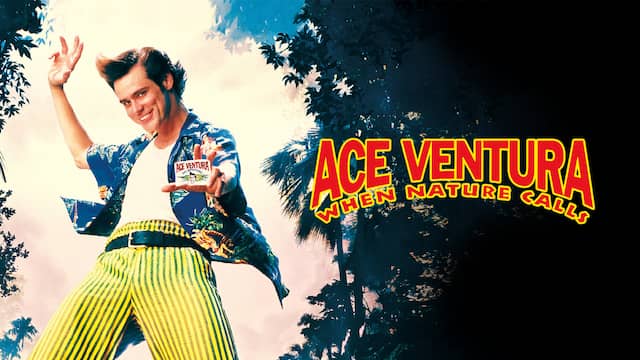 Ace Ventura in yellow pants with stripes blue shirt showing his business card in the jungle