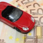 Red Convertible Porsche Toy standing on 50 Euro bills