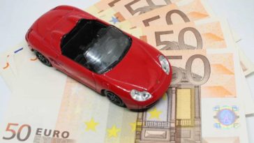 Red Convertible Porsche Toy standing on 50 Euro bills