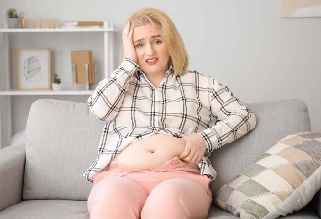 fat blonde woman feeling bad about her big belly