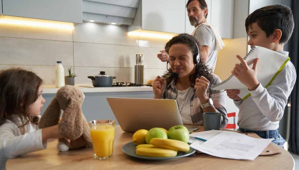 Children annoying a working woman in the kitchen