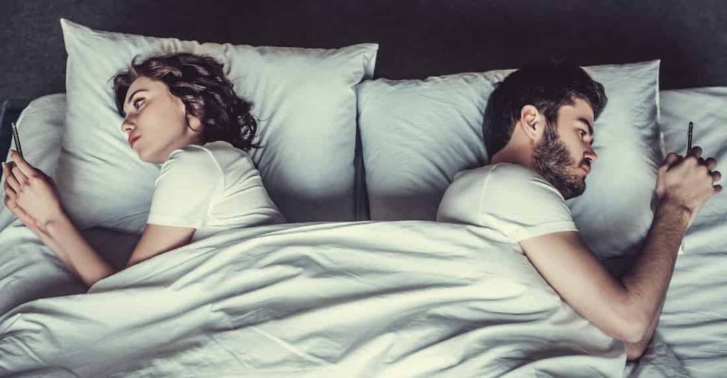 couple in bed watching their phones