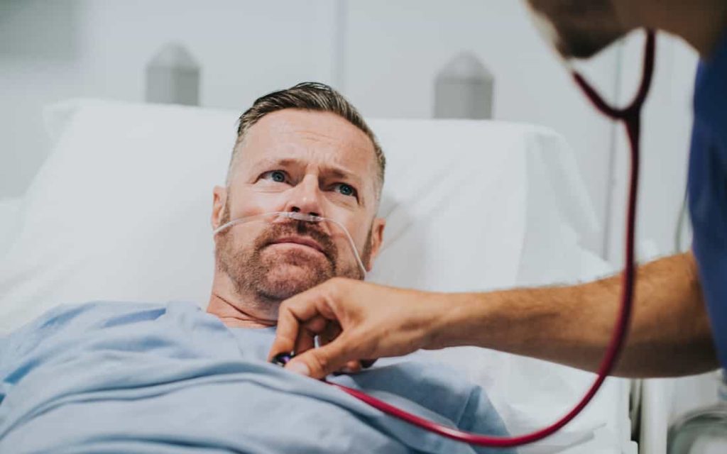 man lying in medical bed is being checked by a doctor