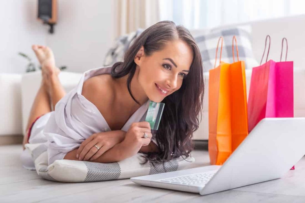 woman lying on her belly while shopping online