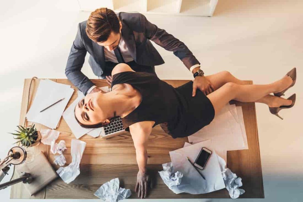 man sexually touching a woman on his desk
