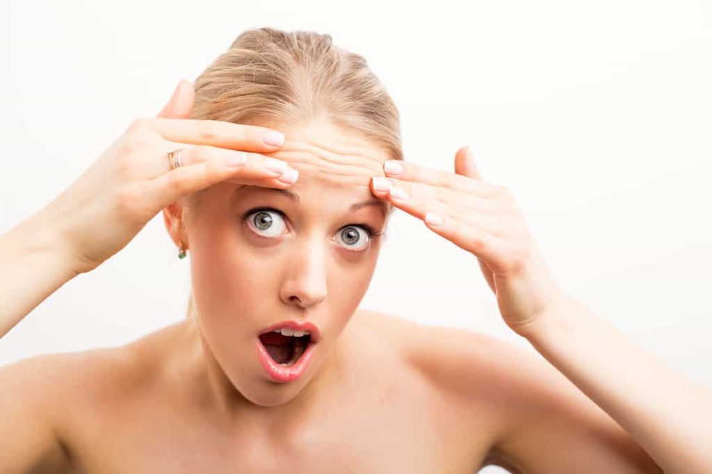 concerned blonde woman about a wrinkle on her forehead