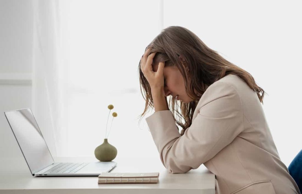 tired woman sitting on desk in front of her laptop