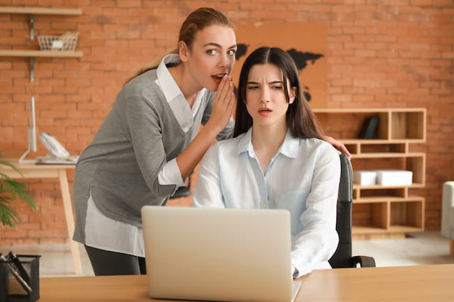 two women gossip at workplace office